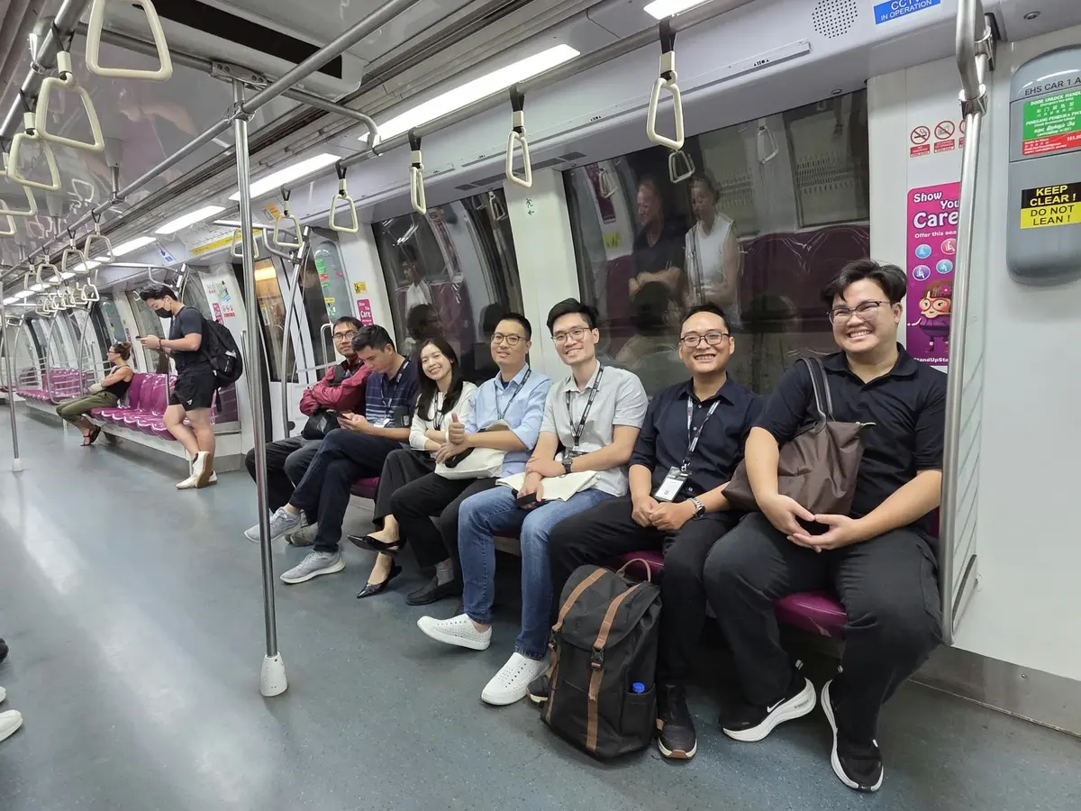 Harry and colleagues sitting together on a Metro train in Singapore during Tech Week.